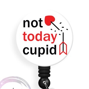 May include: White round badge reel with a black retractable cord and a clear plastic clip. The badge features a red heart with an arrow through it and the text "not today cupid".