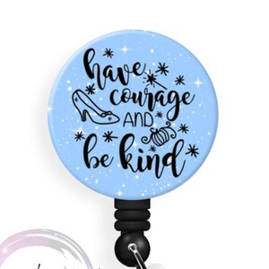 May include: A blue and white glitter badge reel with a black retractable cord. The front of the reel features a Cinderella glass slipper, a magic wand, and the text "have courage and be kind".