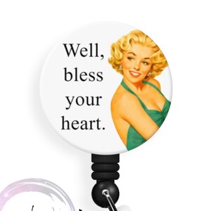 May include: A white badge reel with the text "Well, bless your heart." features a vintage illustration of a woman in a green dress. The reel has a black cord and a clear plastic clip. The Badge Whimsy logo is at the bottom.
