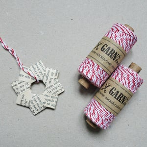 May include: Two spools of red and white baker's twine with the text "GARN & THINE - BACKER - GARN - HINE" on the label.