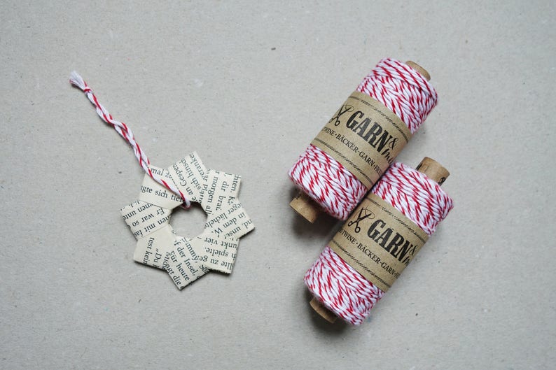 May include: Two spools of red and white baker's twine with the text "GARN & THINE - BACKER - GARN - HINE" on the label.