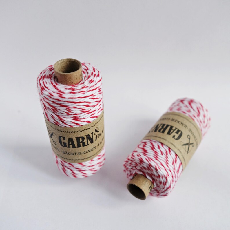 May include: Two spools of red and white baker's twine with brown paper labels that say "GARN & TR&Aring;D" and "NATURLIG B&Auml;CKER-GARN F&Ouml;R...