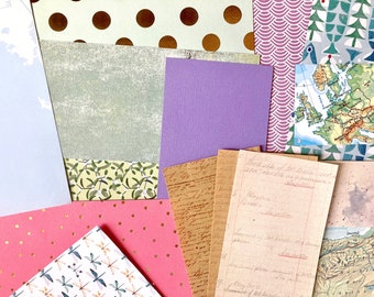 Op de afbeelding: Assortiment van gepatroneerd papier in verschillende kleuren en ontwerpen, waaronder een kaart, een vel met handgeschreven tekst en een vel met een bloemenpatroon.