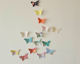 May include: A wall decorated with a variety of colorful butterfly cutouts. The butterflies are arranged in a pyramid shape, with the largest butterfly at the top and the smallest butterflies at the bottom.
