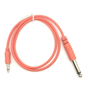 Puede incluir: Un cable de instrumento rosa de 1/4 de pulgada a 1/4 de pulgada con un enchufe recto en un extremo y un enchufe en ángulo recto en el otro extremo.