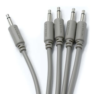 Può includere: Quattro cavi per strumenti grigi da 1/4 di pollice con punte nere e il testo "Modular" stampato su ogni cavo.