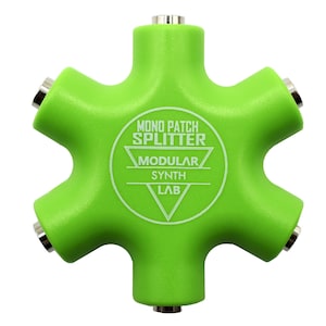 Può includere: Uno splitter per patch mono a sei vie di colore verde lime brillante con sei jack audio metallici. Il centro presenta una scritta bianca che recita MONO PATCH SPLITTER MODULAR SYNTH LAB racchiusa in un design grafico triangolare.