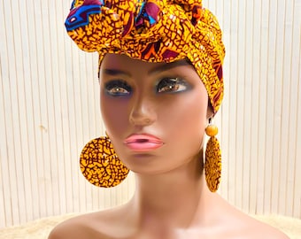 African print head wrap and large disc earrings in a mustard  print with dashes of multi colours.