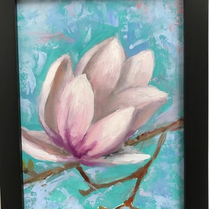 May include: A close-up of a single pink magnolia flower with a light blue background. The flower is in bloom and has a delicate, soft texture.