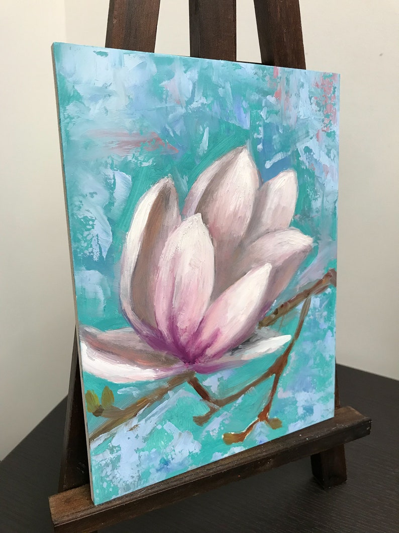 May include: A close-up of a painting of a pink magnolia flower with a light blue background. The flower is painted in a realistic style with visible brushstrokes.