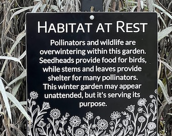 Puede incluir: Un letrero negro con texto blanco que dice "HABITAT AT REST". Describe el papel del jardín para los polinizadores y la fauna silvestre durante el invierno. Ilustraciones florales decoran el borde inferior del letrero.