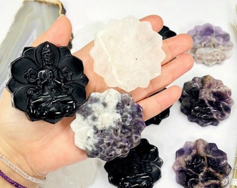 May include: A set of six carved crystal flower-shaped coasters. The coasters are in various colors, including black, white, and purple. The coasters feature a carved design of a Buddha sitting in a lotus position.