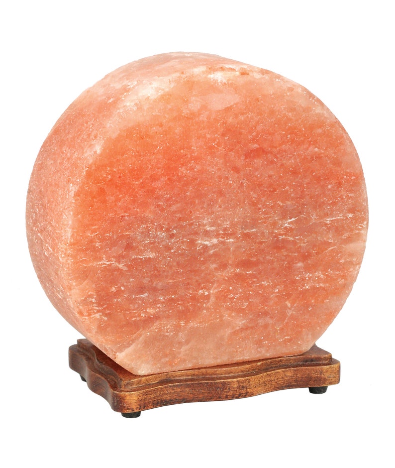 K&ouml;nnte beinhalten: Eine gro&szlig;e, runde Himalaya-Salzlampe mit einem nat&uuml;rlichen, orange-rosa Farbton. Die Lampe steht auf einem Holzsockel mit einem dekorativen Rand.