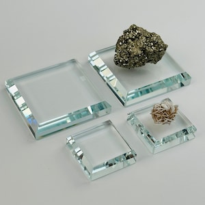 May include: Four clear glass display stands of varying sizes. The largest stand has a rough, dark brown rock on top. The smallest stand has a white, spiky rock on top.