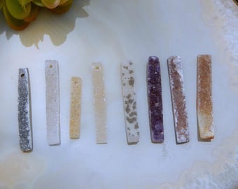 Puede incluir: Un conjunto de diez varillas de cristal de diferentes colores, incluyendo gris, blanco, beige, marrón claro, morado y rosa. Las varillas son todas de tamaño y forma aproximadamente iguales, y están dispuestas en una fila sobre una superficie blanca.
