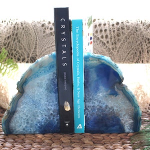 Op de afbeelding: Blauwe agaat boekenleggers met een wit en blauw patroon. De boekenleggers houden twee boeken vast, een getiteld "Crystals" door Janet Harding en de andere getiteld "The Encyclopedia of Crystals, Herbs, & New Age Elements".