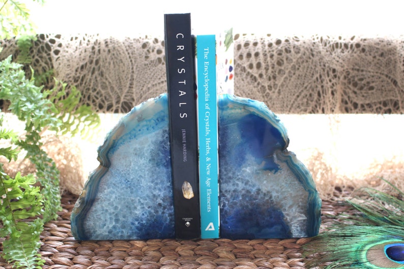 Op de afbeelding: Blauwe agaat boekenleggers met een wit en blauw patroon. De boekenleggers houden twee boeken vast, een getiteld "Crystals" door Janet Harding en de andere getiteld "The Encyclopedia of Crystals, Herbs, & New Age Elements".