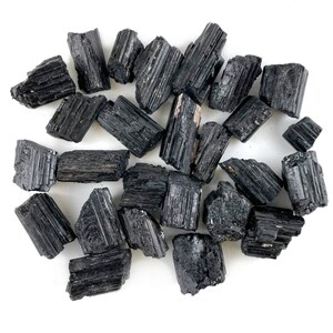 May include: A collection of black tourmaline crystals, also known as schorl, in various sizes and shapes. The crystals are raw and unpolished, with a natural, rough texture.
