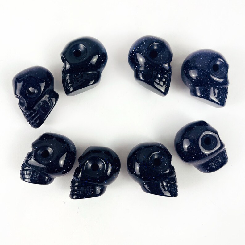 May Include: A collection of Skull Bead-- Purple Goldstone Skull Beads on white surface for reference.