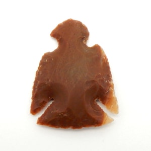 Könnte beinhalten: Ein brauner und orangefarbener Pfeilspitz mit einer spitzen Spitze und einer Kerbe an der Seite. Der Pfeilspitz ist aus Feuerstein und hat eine glatte, polierte Oberfläche.