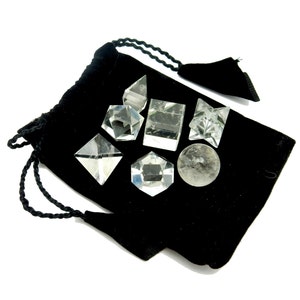 May include: A black velvet pouch containing seven clear quartz crystal shapes, including a sphere, pyramid, cube, and star.