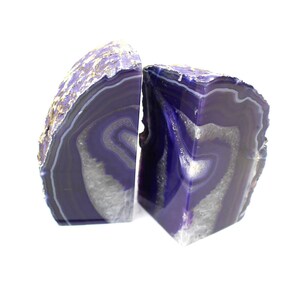 May include: A pair of purple agate bookends with white and gray banding. The bookends are made from natural agate and have a unique, organic shape.