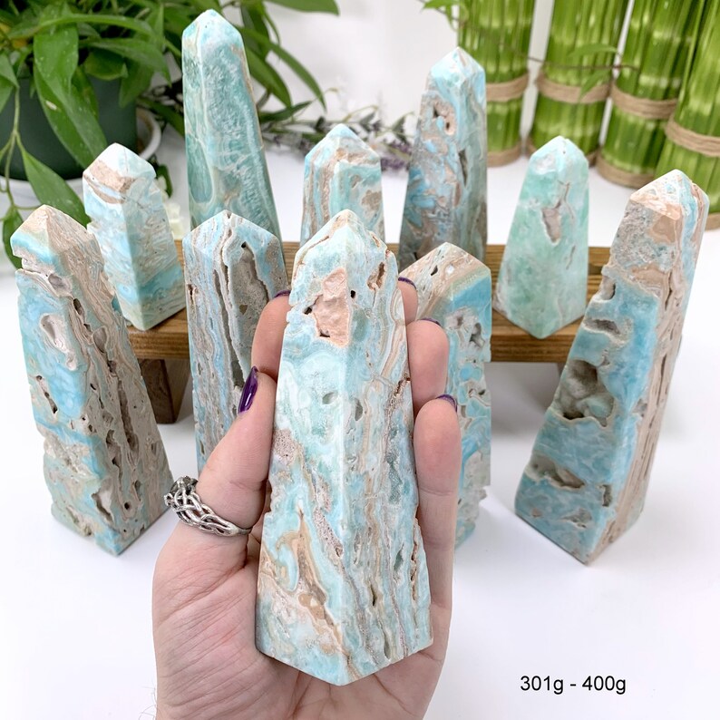 May include: A collection of blue and brown celestite crystal points, also known as "Angel Wing" celestite, arranged on a wooden surface. The crystals are approximately 301 to 400 grams in weight.