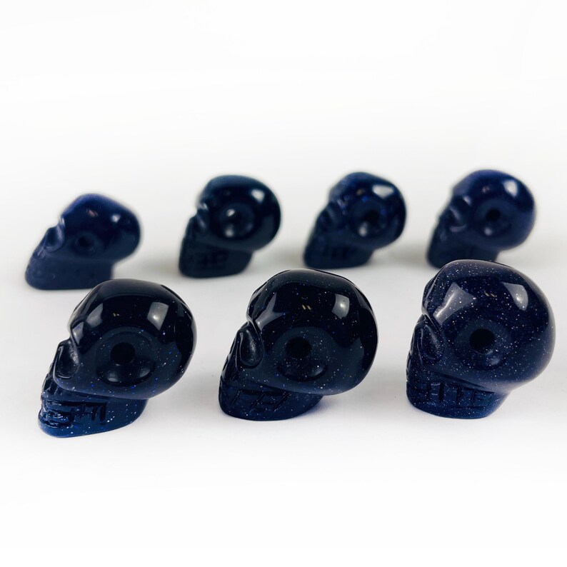 May Include: A collection of Skull Bead-- Purple Goldstone Skull Beads on white surface for reference.