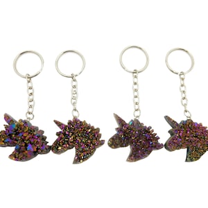 May include: Four iridescent unicorn keychains with silver key rings. The unicorns are made of a glittery, multi-colored material with a purple, pink, and gold color scheme.