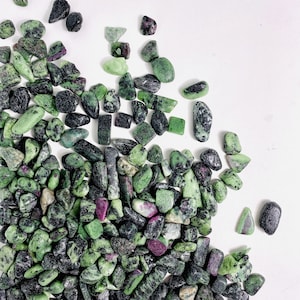 May include: A collection of green and black tumbled stones with a hint of pink. The stones are various sizes and shapes.