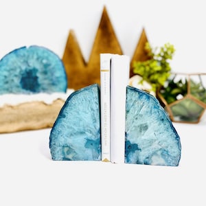 Könnte beinhalten: Ein Paar blaue Achat-Buchstützen, die ein Buch mit dem Titel "Einladung zur Meditation" halten.