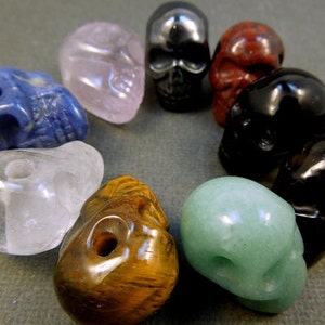 Puede incluir: Una colecci&oacute;n de diez peque&ntilde;as cuentas de cristal en forma de calavera en varios colores, incluyendo transparente, rosa, azul, verde, marr&oacute;n, negro y rojo.