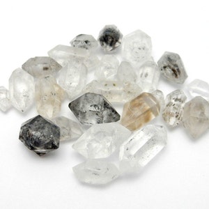 May include: A collection of clear, gray, and brown double-terminated quartz crystals. The crystals are faceted and have a natural, rough texture.
