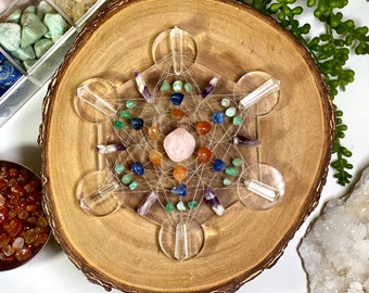 May include: A crystal grid with a variety of crystals, including rose quartz, amethyst, clear quartz, and carnelian. The grid is made of clear acrylic and has a geometric design. The crystals are arranged in a circle around a central rose quartz crystal.