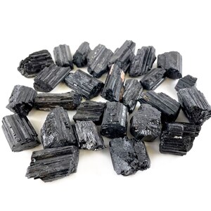 May include: A collection of black tourmaline crystals, also known as schorl, in various sizes and shapes. The crystals are raw and unpolished, with a natural, rough texture.