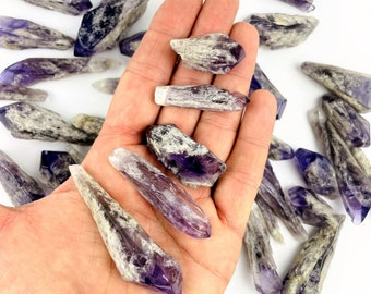 May include: A collection of amethyst crystal points with a purple and white color variation. The crystals are raw and have a natural, rough texture.