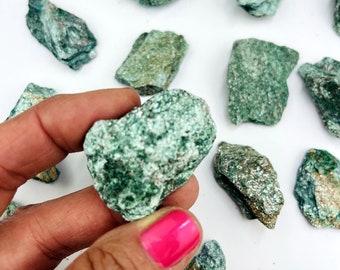 Puede incluir: Una colección de piedras brutas de aventurina verde. Las piedras son de varios tamaños y formas, con una textura brillante y reluciente.