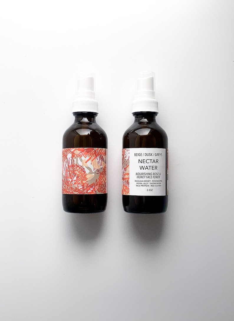 May include: Two brown glass bottles with white spray tops. The bottles have labels with floral designs and text that reads "NECTAR WATER" and "3 oz". The toner contains rose and honey.