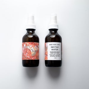 May include: Two brown glass spray bottles with white spray nozzles. The bottles have labels with floral designs and the text "NECTAR WATER" and "NOURISHING ROSE & HONEY FACE TONER". Each bottle contains 3 oz of product.