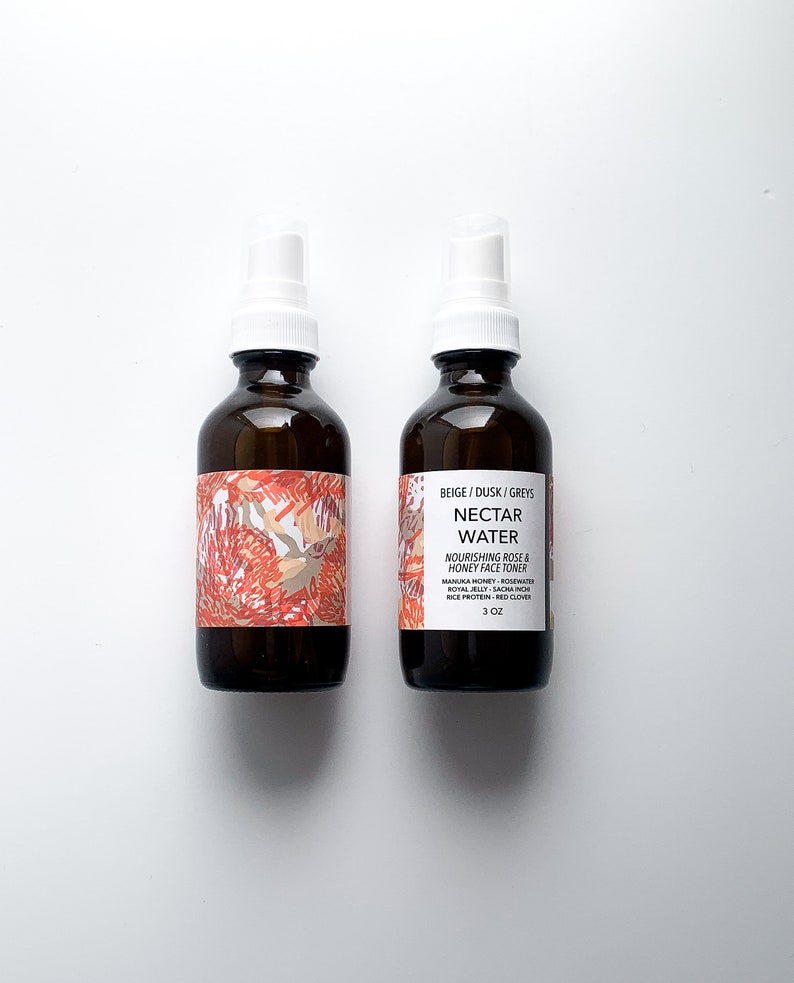 May include: Two brown glass spray bottles with white spray nozzles. The bottles have labels with floral designs and the text "NECTAR WATER" and "NOURISHING ROSE & HONEY FACE TONER". Each bottle contains 3 oz of product.