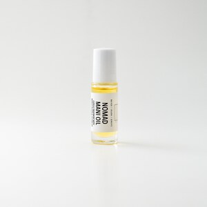 Puede incluir: Una botella de vidrio transparente de Nomad Mani Oil con tapa blanca. La botella contiene un l&iacute;quido amarillo y tiene una etiqueta con el nombre del producto y otro texto. El producto es un tratamiento para cut&iacute;culas.