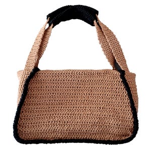 Può includere: Borsa a mano all'uncinetto beige con finiture e manici neri. La borsa rettangolare presenta un motivo a punto strutturato e un rivestimento nero per il comfort. La borsa è progettata con uno stile semplice ma elegante.