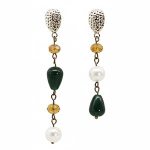 Può includere: Un paio di orecchini pendenti con una parte superiore argentata e strutturata. Ogni orecchino presenta una perla a goccia verde scuro, una perla bianca e perline color ambra. Gli orecchini sono collegati da delicate catene di metallo.