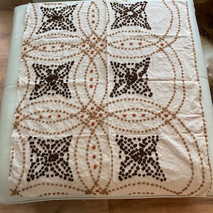 May include: Cream-colored textile with a repeating pattern of dark brown and tan dots and circles. The design features four large, star-like shapes filled with dark brown dots, connected by tan dotted lines.