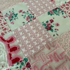 May include: A patchwork quilt featuring squares of various pink and white fabrics. Some squares have floral patterns, others have teddy bear designs, and some have textured embroidery. The quilt has a vintage, handmade aesthetic.