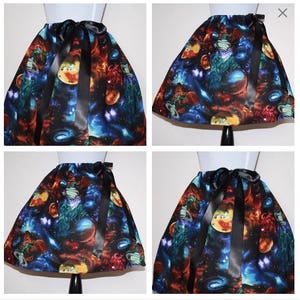 May include: A black skirt with a colourful space-themed print featuring planets, stars, and galaxies. The skirt has a black satin ribbon tied at the waist.