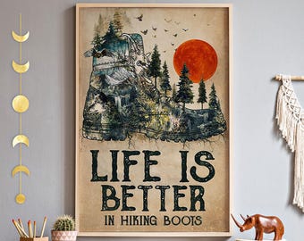 May include: Framed poster featuring a hiking boot design filled with a forest scene, a waterfall, and a red sun. The text reads "LIFE IS BETTER IN HIKING BOOTS". The poster is in a wooden frame.