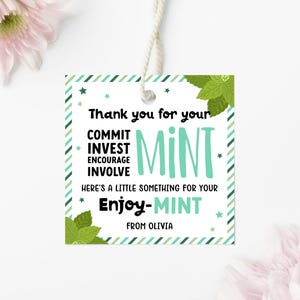 May include: A square gift tag with a white background, green striped borders, and green mint leaf illustrations. The text reads: Thank you for your COMMIT INVEST ENCOURAGE INVOLVE MINT HERE'S A LITTLE SOMETHING FOR YOUR Enjoy-MINT FROM OLIVIA.