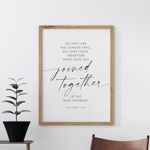 May include: A framed print with the text "So they are no longer two, but one flesh. Therefore what God has joined together, let no man separate." A brown leather chair and a decorative cart with candles and a plant are also in the image.