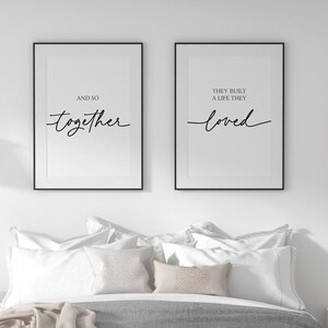 May include: A bedroom with a gray and white bed, two black framed prints with the text "And so together" and "They built a life they loved", a wooden nightstand with a lamp, and a rug on the floor.